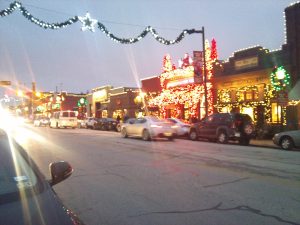 Downtown Grapevine decorated for Christmas, with a row of old buildings covered in lights and a lighted garland over the street.