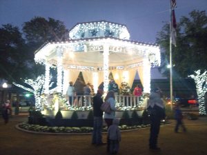 A gazebo in a small-town park is lit up with white Christmas lights