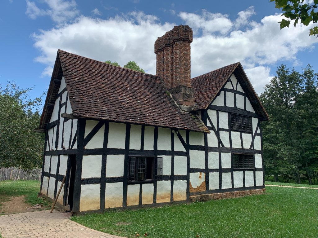 A half-timbered building, white plaster with dark brown timbers and a brick chimney.