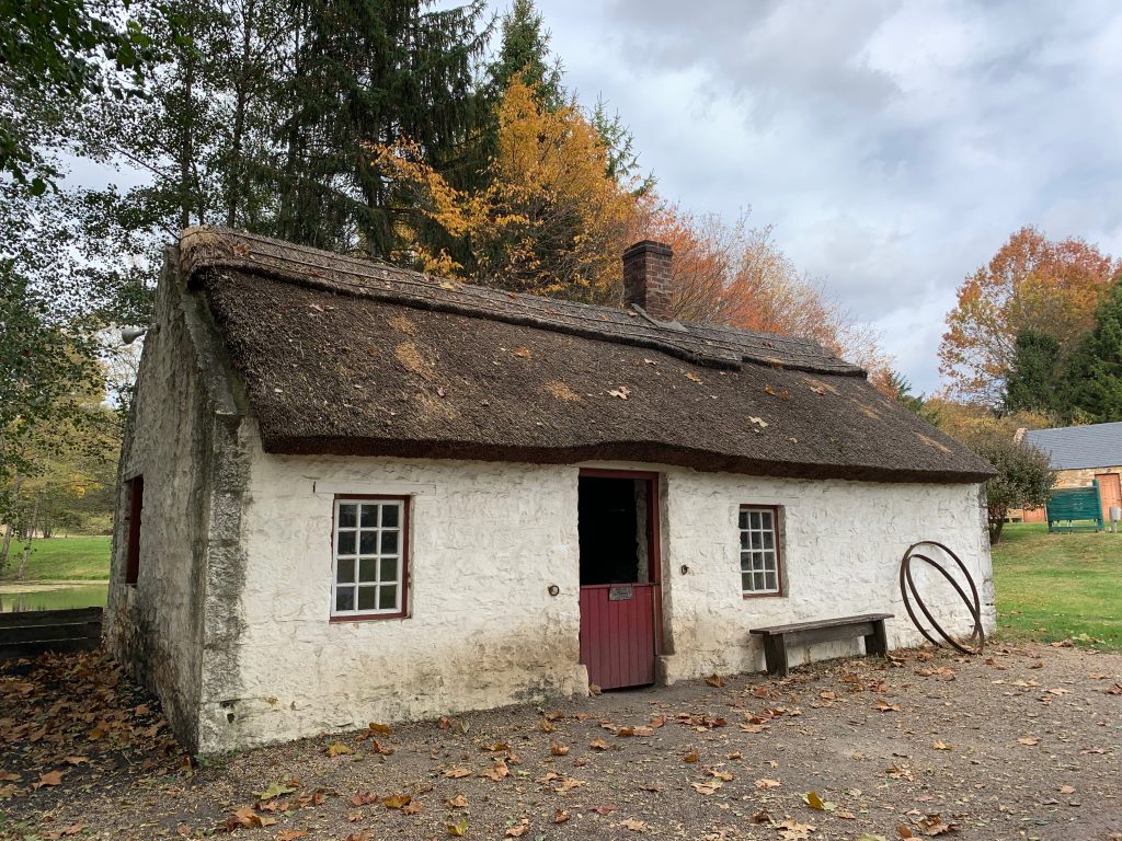 A white stone forge building with a thatched roof.