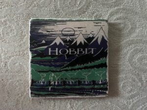 A stone coaster with the original illustrated cover of The Hobbit on it.