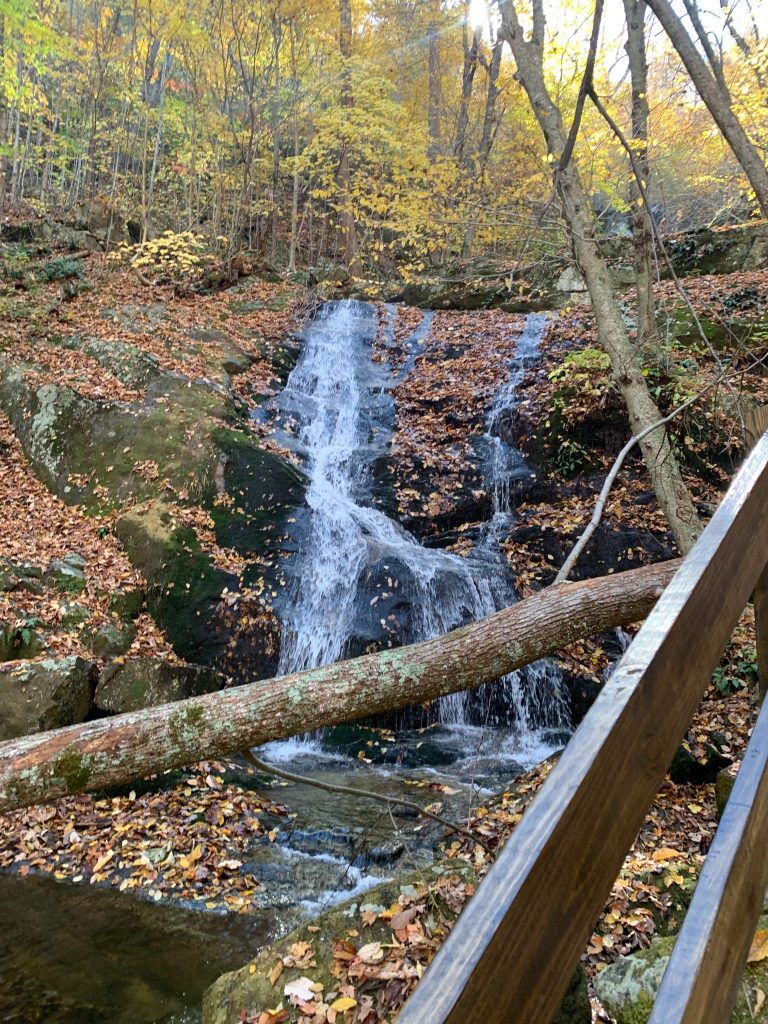 A waterfall with multiple streams flows down rocks in a wooded area.